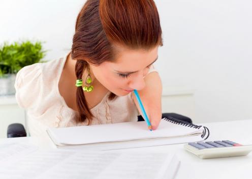 A woman with limb difference uses a pencil to write